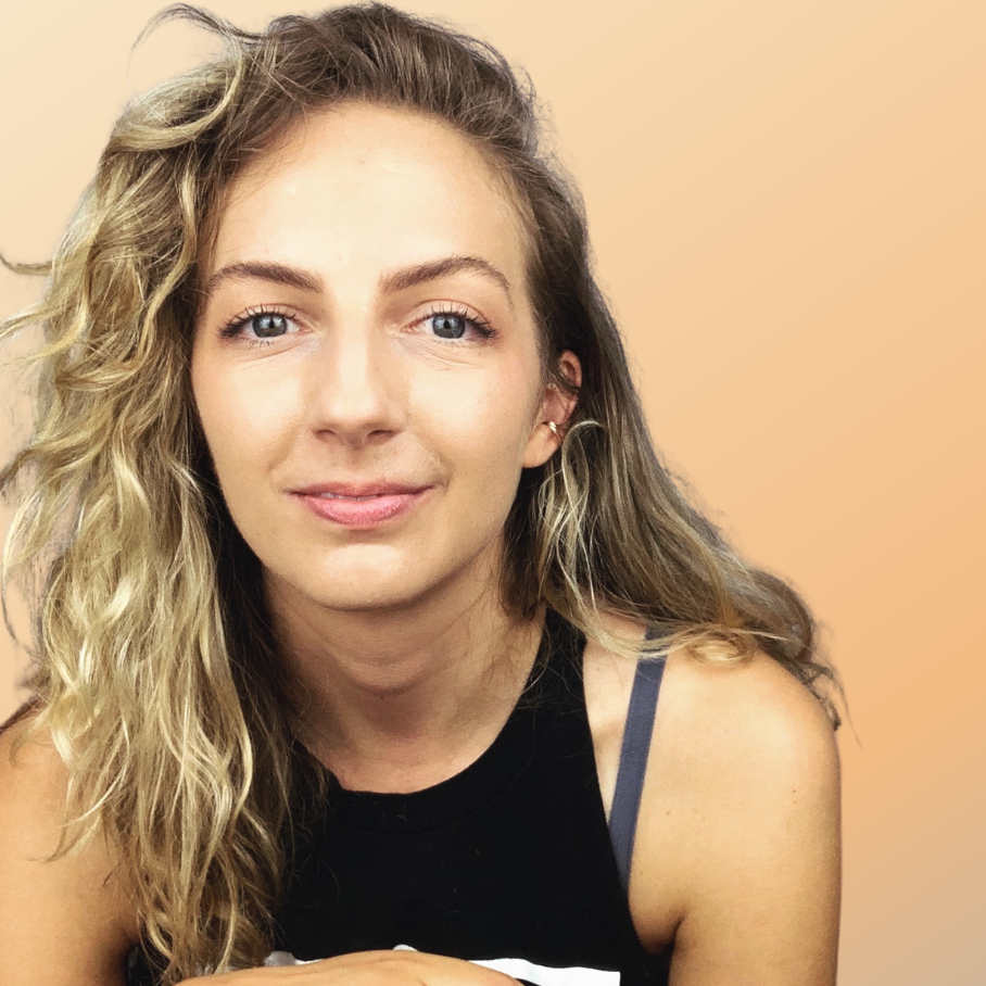 a woman with curly blonde hair in a black tank top looking serenely at the camera.